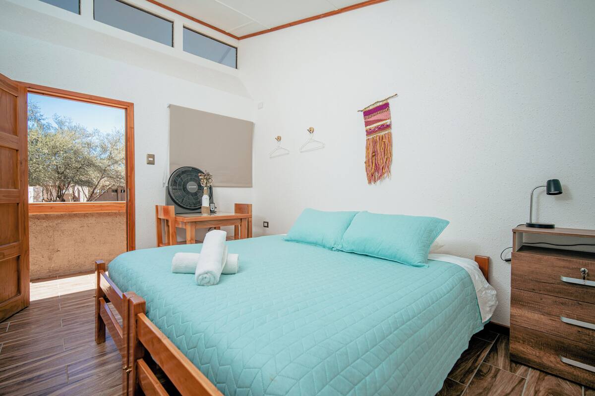 Une chambre à coucher avec un lit, une commode en bois et un bureau avec une chaise.