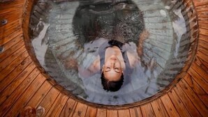A wooden hot tub with a stone wall in the background. - Hotel Tantakuy Eco Experience (Pozo Almonte)