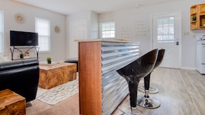 A modern kitchen with a wooden countertop, a built-in oven, and a dining area with two black chairs.