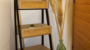 Een houten wandplank met drie planken, een kleine potplant en pluimgras in een groene glazen vaas, voor een witte muur.