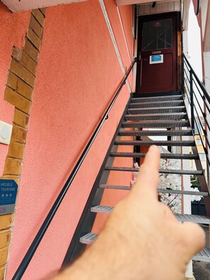 A staircase leading to a door with a sign indicating a touristic area. - L'instant T 4* Balneotherapy, Sauna, and Private Parking (Colmar)