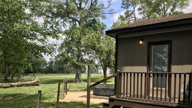 A cabin with a wooden deck, a small porch, and a window. - Secluded Cottage on Cattle Farm and Dog Friendly All Sizes (Vienna)