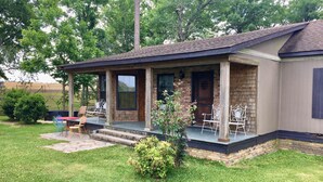 A single-story house with a covered porch, brick exterior, and a small front yard. - Secluded Cottage on Cattle Farm and Dog Friendly All Sizes (Vienna)