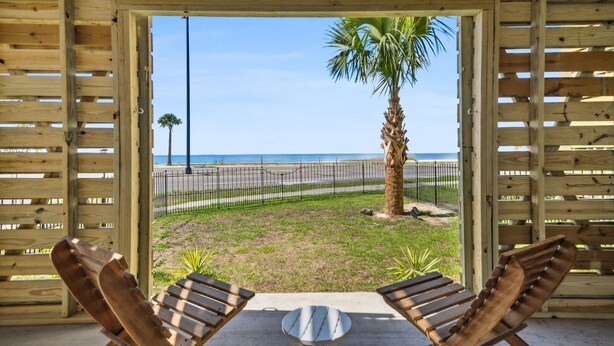 A wooden pergola with a view of the beach and palm trees.