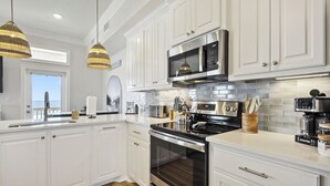 A modern kitchen with white cabinetry, stainless steel appliances, and a view to the outside.