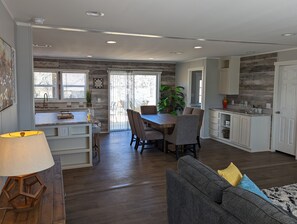 A modern kitchen with a dining area, wooden flooring, and a large window.