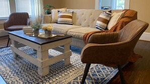 Un salon comprenant un canapé, deux fauteuils, une table basse et un tapis à motifs.