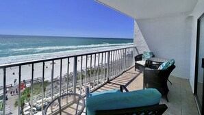 A balcony with a view of the beach and ocean. There are wicker chairs and a table. - Enjoy “BEACH LIFE”.  Breathtaking Beach Front Condo, Great Balcony & Amenities! (Panama City Beach)
