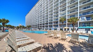 A hotel with a large pool area, multiple balconies, and sun loungers. - Enjoy “BEACH LIFE”.  Breathtaking Beach Front Condo, Great Balcony & Amenities! (Panama City Beach)