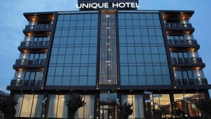 Un hôtel moderne, avec une façade en verre, de nombreux balcons et une entrée imposante.