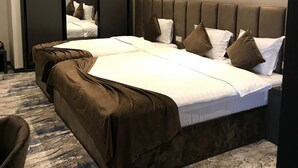 Une chambre d’hôtel avec un grand lit, deux tables de chevet, un miroir et un sol recouvert de moquette.