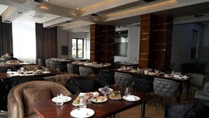 Un vaste espace dédié à la salle à manger, avec de nombreuses tables et chaises, une grande fenêtre et un aménagement intérieur moderne.