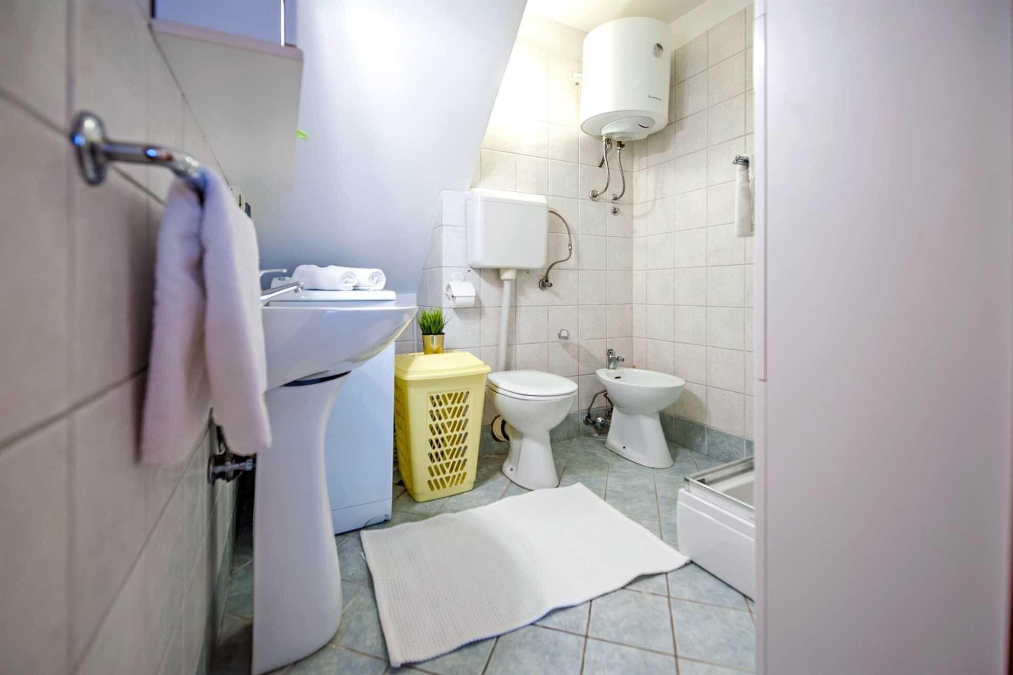 Een kleine badkamer met toilet, bidet en een wit wastafel.