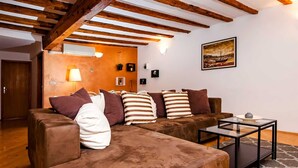 Una sala de estar acogedora con un sofá seccional marrón, una mesa de centro de vidrio y un cuadro en la pared.