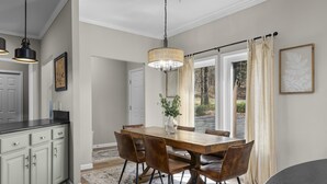 Un comedor con una mesa de madera, sillas marrones y una lámpara colgante.