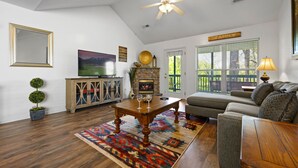 A living room with a fireplace, a sofa, a coffee table, and a TV. - Bright and Breezy Riverfront Chalet (Pigeon Forge)