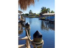 Enjoy serene waterfront views from this tranquil retreat, featuring a dock and picturesque palm trees.
