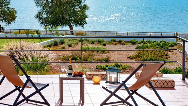 A terrace with two lounge chairs, a table with a bottle and snacks, a lantern, and a view of the sea. - Villa Sea Sand - Sunset View Beachfront Villa Near Tavernas & Shops (CHANIA)