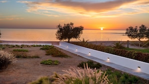 A coastal walkway with a sunset view, a white railing, and landscaped areas. - Villa Sea Sand - Sunset View Beachfront Villa Near Tavernas & Shops (CHANIA)