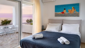 A bedroom with a bed, pillows, and a painting of a beach scene. - Villa Sea Sand - Sunset View Beachfront Villa Near Tavernas & Shops (CHANIA)
