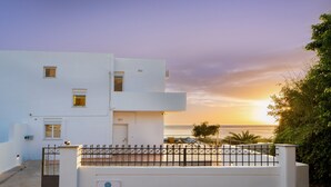 A white building with a gated entrance, a small balcony, and a sign that reads "SEASAND." - Villa Sea Sand - Sunset View Beachfront Villa Near Tavernas & Shops (CHANIA)