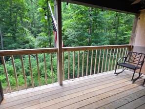 A wooden deck with a metal railing, a flag, and a bench.
