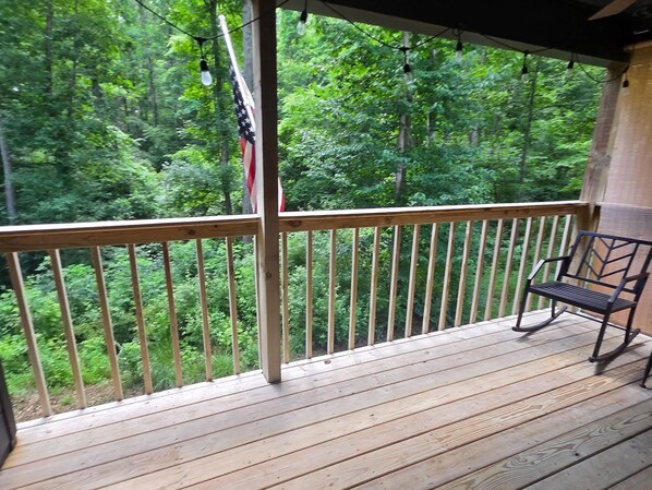Une terrasse en bois avec une rambarde en métal, un drapeau et un banc.