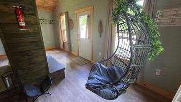 A room with a hanging chair, a fire extinguisher, a bench, and a door.