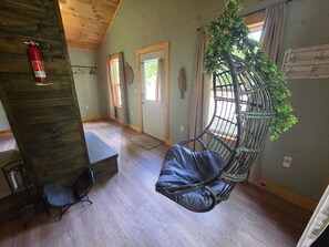 A room with a hanging chair, a fire extinguisher, a bench, and a door.