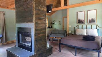 A cozy bedroom with a fireplace, a bed, a sofa, and a small table.