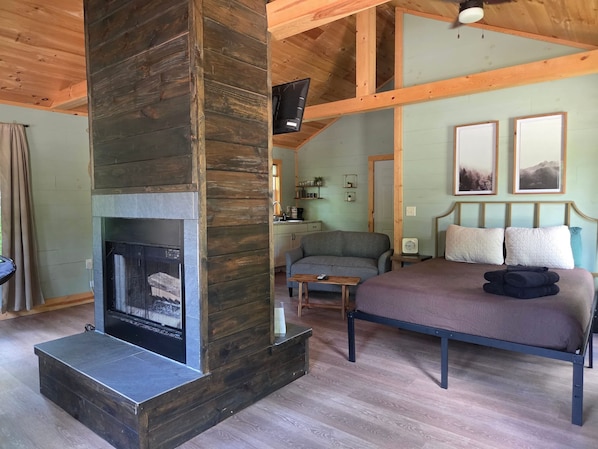 Un dormitorio acogedor con chimenea, una cama, un sofá y una mesita.