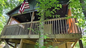 A wooden cabin with a balcony, surrounded by trees. - Firefly Landing at Avenwood Cabins (New Straitsville)