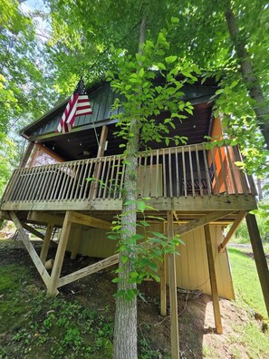 A wooden cabin with a balcony, surrounded by trees. - Firefly Landing at Avenwood Cabins (New Straitsville)