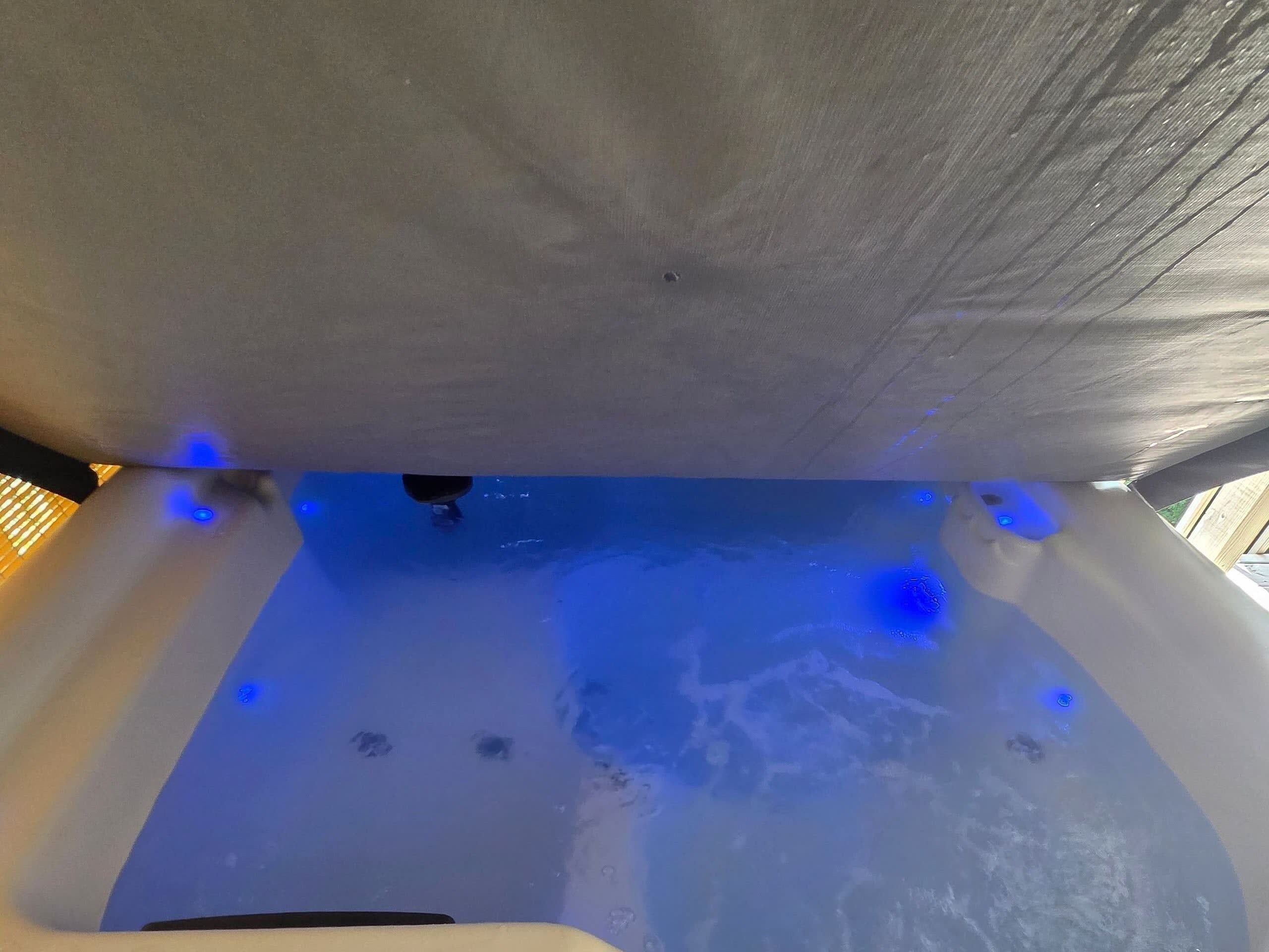 A hot tub with blue lighting and a wooden deck.