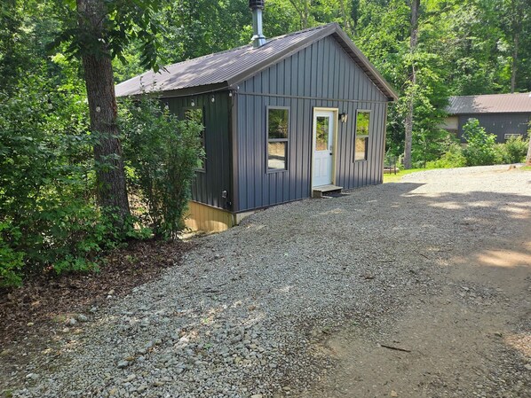 A small, single-story building with a metal roof and a gravel driveway.