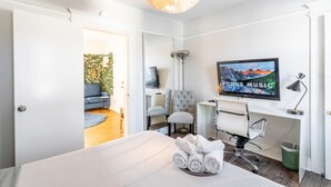 Ein modernes Hotelzimmer mit Bett, Schreibtisch, Stuhl, Fernseher und einer Tür zu einem Balkon.