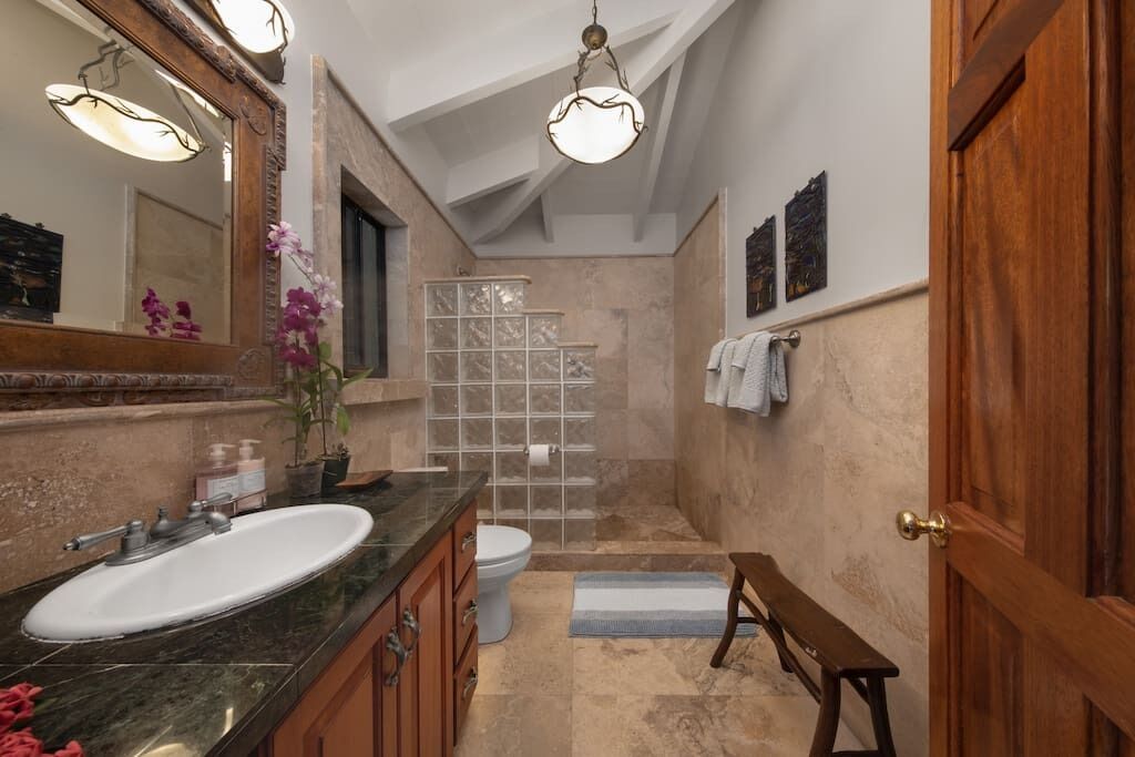 Un baño con lavamanos grande, espejo y ducha.