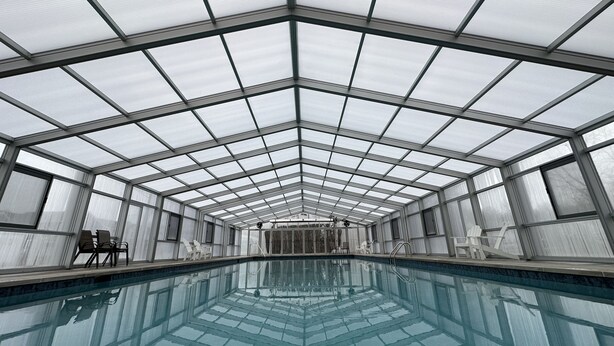 A large indoor swimming pool with a glass ceiling, surrounded by seating areas.