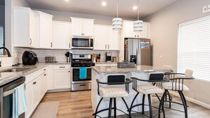 A modern kitchen with white cabinets, stainless steel appliances, and a central island with bar stools.