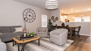 A living room with a sofa, armchair, coffee table, and dining area with a table and chairs.