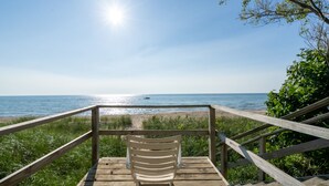 En træterrasse med en hvid stol med udsigt over stranden.