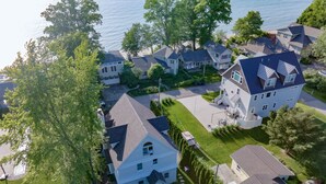 Oversigtsbillede af et boligområde med huse, en stor hvid bygning med et blåt tag og et vandområde i baggrunden.