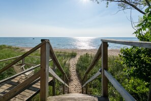 A wooden staircase leading to a beach with a clear view of the ocean.