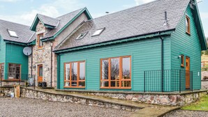 A two-story building with a green exterior and a stone foundation. - 2 bedroom accommodation in Blairgowrie (Blairgowrie)
