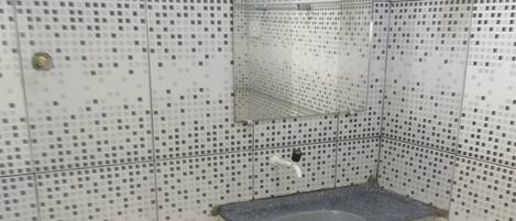 Ein kleines Badezimmer mit Waschbecken, Toilette und einem gelben Eimer.
