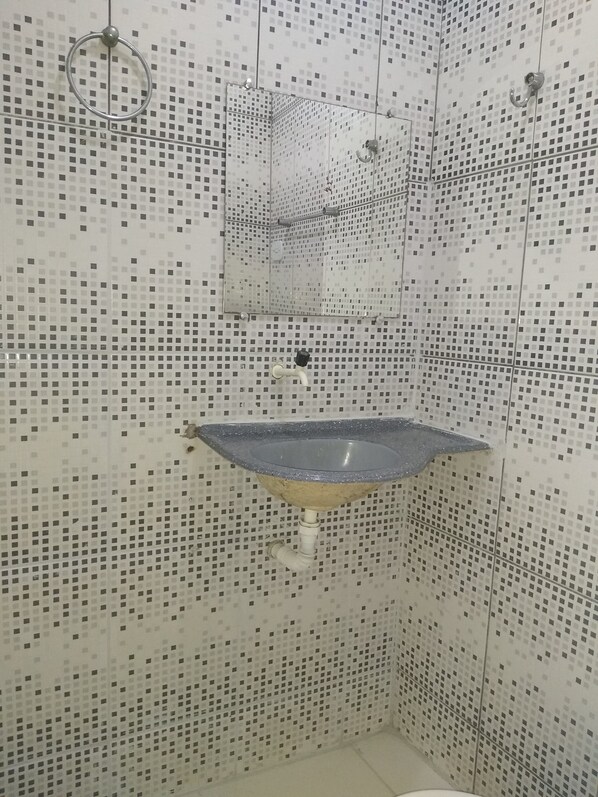 Un baño con pared de mosaicos, un lavamanos y zona de ducha.
