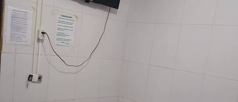 Une petite pièce comprenant un lit, un téléviseur fixé au mur et un panneau d’information.