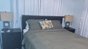 A neatly arranged bedroom with a bed, two bedside tables, and a green rug. - 15 MINUTES WALK TO THE BEACH (Nassau)