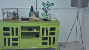 A green entertainment center with a flat-screen TV mounted above it, a framed picture, a small figurine, and a decorative item on top. - 15 MINUTES WALK TO THE BEACH (Nassau)