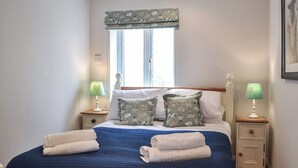 Ein ordentlich bezogenes Bett mit blauer Bettwäsche, zwei Kissen mit Muster und zwei Nachttischlampen.